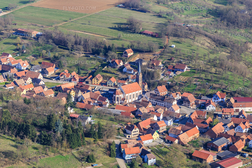Aerial view: Church building of Église Saint-Nabor in the village center in Ettendorf in the state Bas-Rhin, France. – Photo: IMG_097514.jpg taken on 03/16/2017 by Werner Riehm/FLY-FOTO.com – Resolution of the original: 5388 x 3592 px