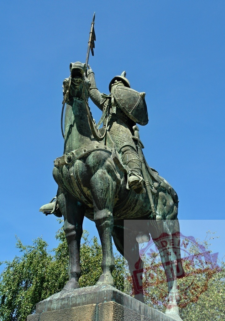 Bronze equestrian statue of a knight with spear | Bronze statue of a historic knight on horseback with a shield and spear against blue sky - Realisiert mit Pictrs.com