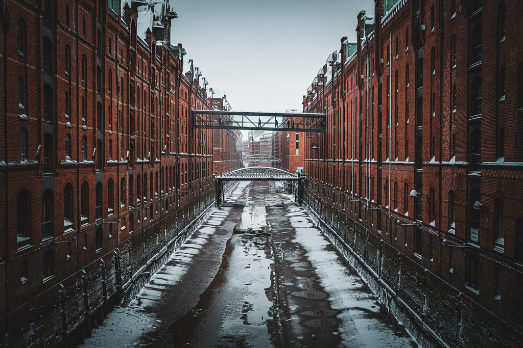 Eisige Leere: Sturmebbe in der Speicherstadt | Dieses Motiv zeigt die Speicherstadt während einer Sturmebbe. Wo sonst das Wasser der Elbe steht, sind nur gefrorene Pfützen und der Grund der Fleete zu sehen. Eine Momentaufnahme bei extremem Frost und Ostwind. - Realisiert mit Pictrs.com