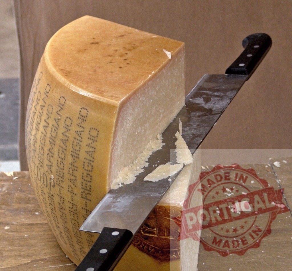 Parmigiano Reggiano cheese being cut with knife | Parmigiano Reggiano, an Italian hard cheese, is being broken down - Realized with Pictrs.com