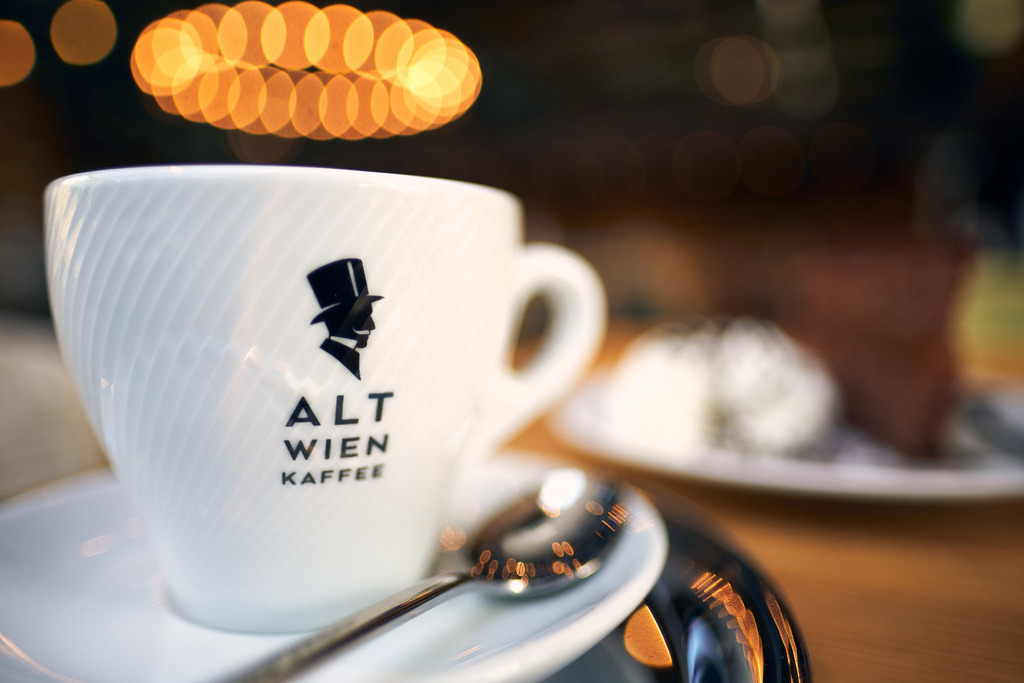 Luftburg Kolarik, eine Tasse Melange auf dem Tisch stehend | WIen, Austria - February 24, 2022; Luftburg Kolarik, eine Tasse Melange auf dem Tisch stehend, im Hintergrund eine Sachertorte. - Realisiert mit Pictrs.com