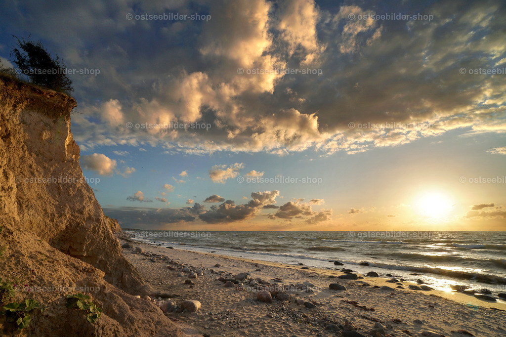 Magie des Moments | Das Bild zeigt einen Sonnenuntergang mit einem faszinierenden Abendhimmel über der Ostsee. Im Vordergrund werden Steilküste und Strand in ein warmes Licht gehüllt.
