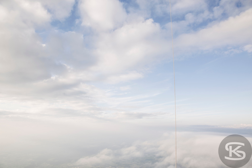 Luftaufnahme einer Ballonfahrt: Sanfte Wolkendecke & Blauer Himmel – Naturfoto | Hochauflösende Luftaufnahme einer dichten, weißen Wolkendecke, die eine heitere und verträumte Atmosphäre schafft. Perfektes Natur- und Reisebild. Ballonfahrt - Realisiert mit Pictrs.com