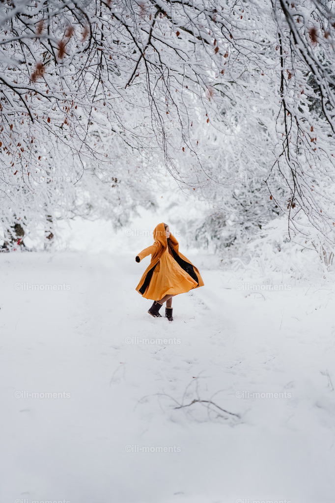 Tanz im Schnee | Ein fröhliches Mädchen tanzt im weißen Schnee, ihr leuchtend gelber Mantel strahlt Lebensfreude und Leichtigkeit aus. Dieses ausdrucksstarke Fotokunstwerk bringt Farbe und Bewegung in jede winterliche Raumgestaltung. - Realisiert mit Pictrs.com