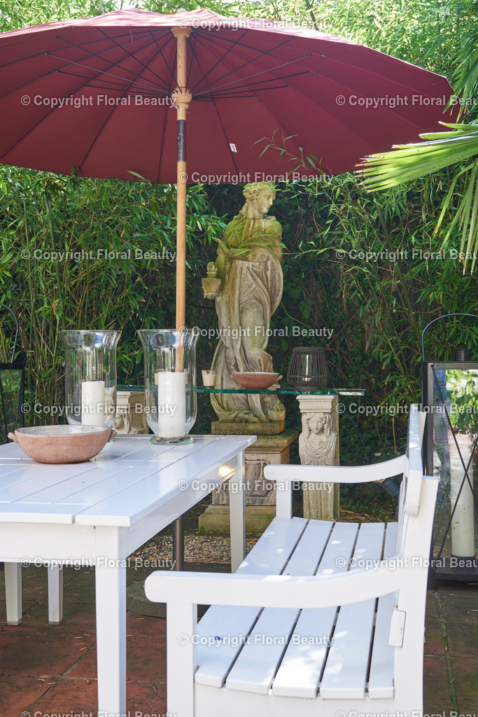 Mediterraner Stadtgarten | asiatisch anmutende Terrasse mit weißen Gartenmöbeln und rotem Sonnenschirm - Realisiert mit Pictrs.com
