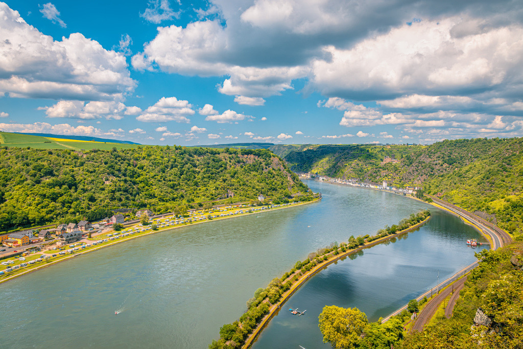Panoramablick auf weltberühmten Loreleyfelsen,Obere Mittelrheintal | Das Bild zeigt den weltberühmten Loreleyfelsen und das Obere Mittelrheintal bei St. Goarshausen am Rhein.UNESCO-Welterbe: Der abgebildete Flussabschnitt gehört seit 2002 zum UNESCO-Welterbe Oberes Mittelrheintal, das für seine einzigartige Kulturlandschaft mit vielen Burgen und Weinbergen bekannt ist.Die Loreley-Sage: Der 125 Meter hohe Schieferfelsen zieht Touristen aus aller Welt an. Der Legende nach verzauberte eine Nixe namens Loreley die Schiffer mit ihrem Gesang, woraufhin diese an den gefährlichen Felsenriffen zerschellten - Realisiert mit Pictrs.com