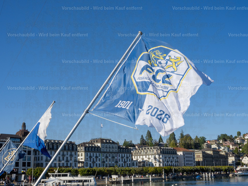 125 Jahre FCL – Luzern in Blau-Weiss | Die blau-weissen Fahnen wehen an der Seebrücke im Wind und zelebrieren das 125-Jahre-Jubiläum des FC Luzern. Dahinter erstreckt sich die Kulisse der Luzerner Seepromenade mit dem traditionsreichen Hotel Schweizerhof. - Realisiert mit Pictrs.com