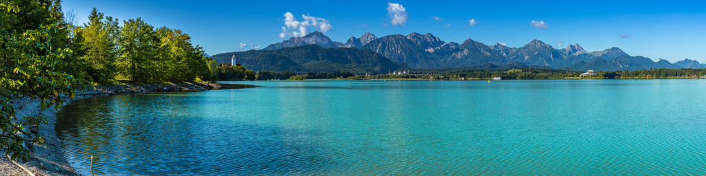 Allgäu Wandbild - Forggensee Panorama | Hier ein wunderschönes Panorama des Forggensees mit Blick auf die Kirche von Waltenhofen, Füssen und im Hintergrund die Tannheimer Berge. Dieses Panorama eignet sich am Besten für ein Seitenverhältnis von 4:1 und solltet Ihr es Euch riesengroß drucken lassen wollen, schreibt mir einfach eine Nachricht, es liegt auch in noch höherer Auflösung vor. In der online-verfügbaren Auflösung kann man es locker zwischen 200-300cm Breite drucken lassen.