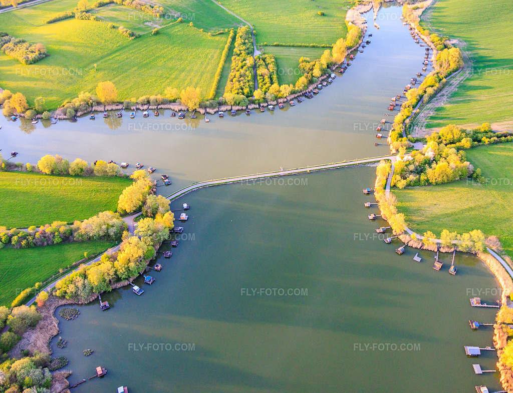 Aerial view: Bridge over the lake Etang du Welschhof in Puttelange-aux-Lacs in the state Moselle, France. – Photo: IMG_154809.jpg taken on 04/17/2026 by Werner Riehm/FLY-FOTO.com – Resolution of the original: 5219 x 4000 px