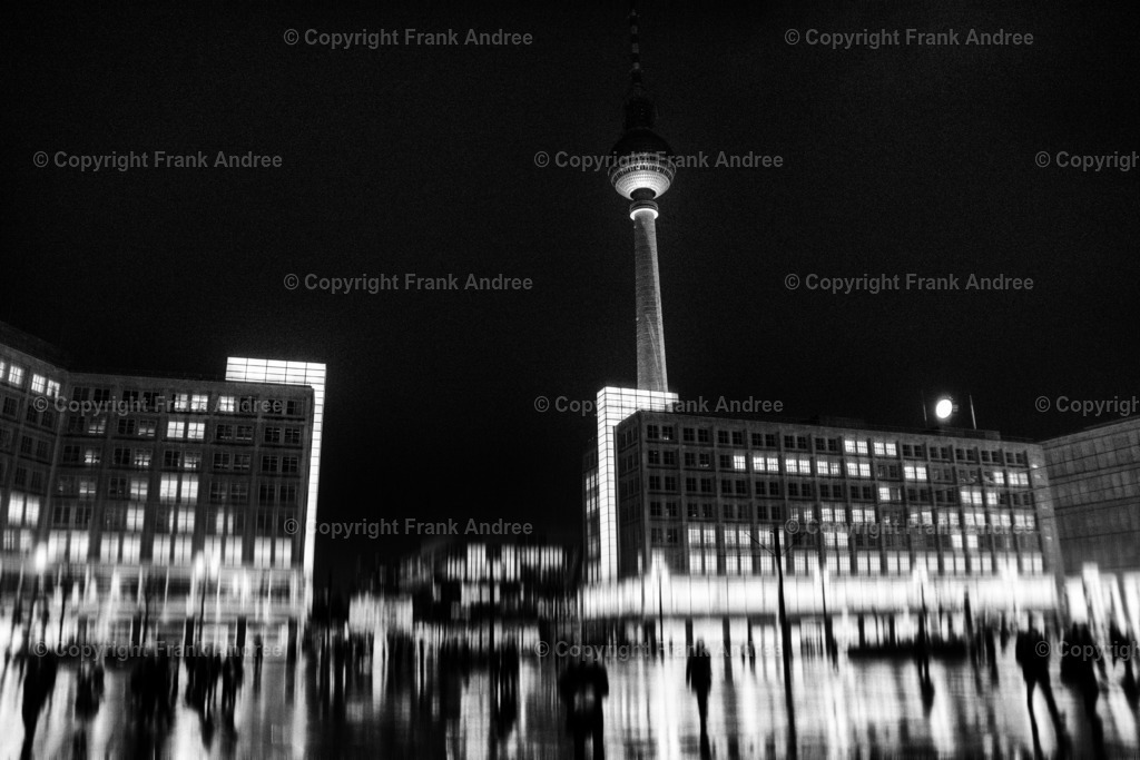 Alexanderplatz Berlin | Eine regnerische Nacht in Berlin. Menschen gehen über den nassen beleuchteten Alexanderplatz in der Mitte Berlins. Nachtfotografie aus Berlin in schwarz und weiß. - Realisiert mit Pictrs.com