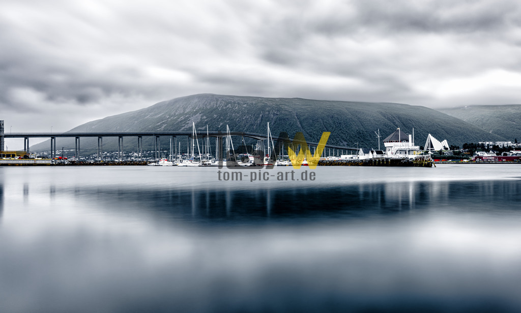 Stadtansicht von Tromsø mit der Tromsø-Brücke (Tromsøbrua) | Das Bild zeigt die Tromsø-Brücke (Tromsøbrua) in der nordnorwegischen Stadt Tromsø. Die Brücke verbindet das Stadtzentrum auf der Insel Tromsøya mit dem Stadtteil Tromsdalen auf dem Festland. - Realisiert mit Pictrs.com