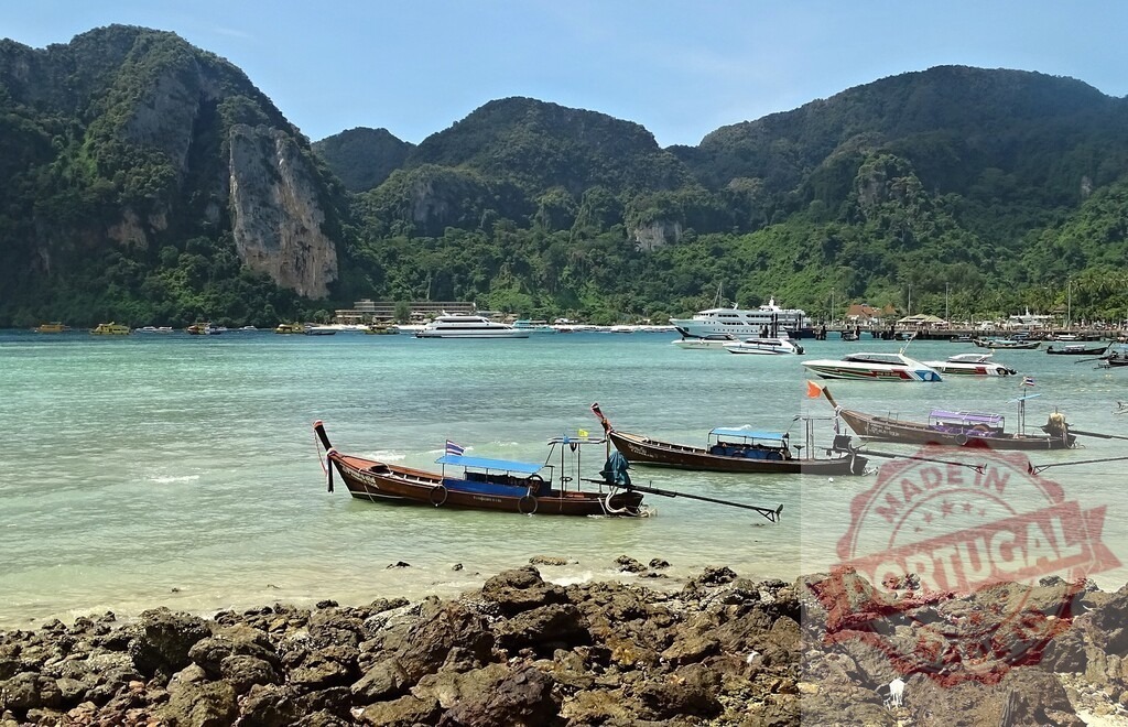 Traditional longtail boats resting on Phi Phi Island, Thailand, with cruise ships in the background | Longtail boats floating near the shore of Phi Phi Island in Thailand, with cruise ships and forested hills adding to the idyllic scene - Realized with Pictrs.com