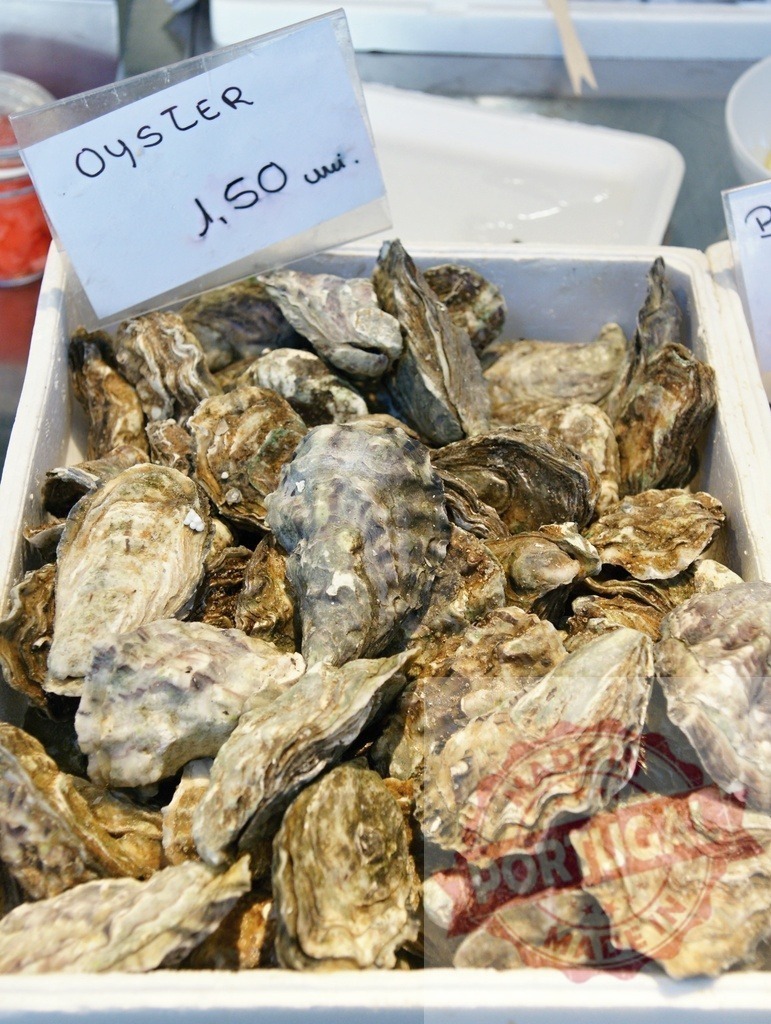 Fresh oysters for sale at a seafood market | Oysters in their shells displayed with a price tag at a fish market stall - Realisiert mit Pictrs.com