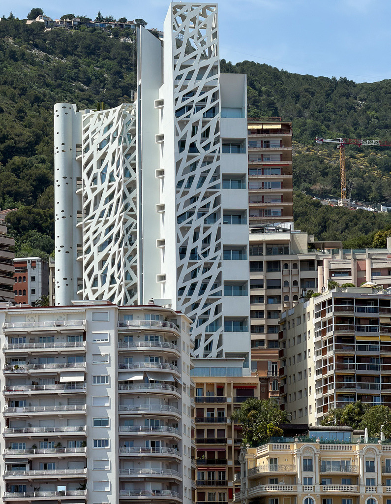 Le Simona – Organische Geometrie in Weiß | Meisterhafte moderne Architektur in absoluter Perfektion. Diese kontrastreiche Aufnahme zeigt die spektakuläre, perforierte weiße Betonfassade des berühmten Luxusturms „Le Simona“ in Monaco. Das faszinierende Zusammenspiel aus geschwungenen Linien, quadratischen Aussparungen und dem strahlenden Weiß vor dem mediterranen Hintergrund bringt urbane High-End-Eleganz an jede Wand. Ein exklusives Highlight als großformatiger Fine Art Print, edles Alu-Dibond oder unter Acrylglas für minimalistische Lofts und designorientierte Büros. - Realisiert mit Pictrs.com
