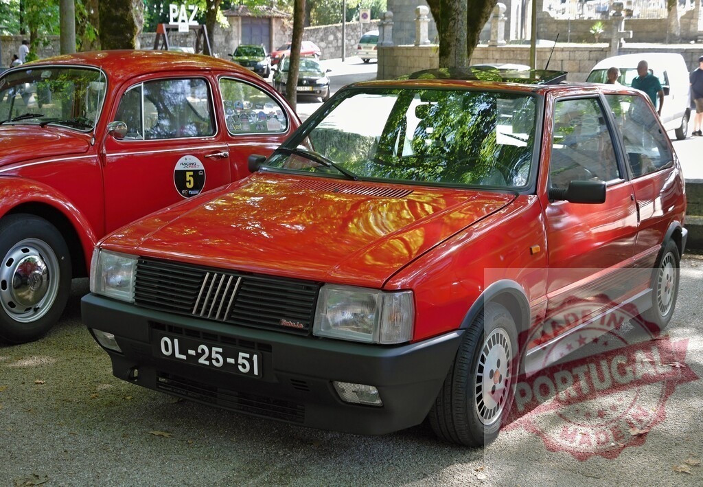 Red Fiat Uno Turbo ie vintage car display | Red Fiat Uno Turbo ie classic car parked at a public outdoor event - Realized with Pictrs.com