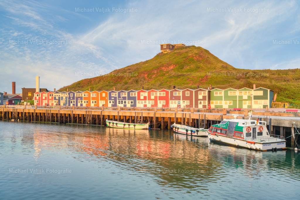 Hummerbuden auf Helgoland | Blick auf die Hummerbuden auf Helgoland, die von der frühen Morgensonne angeleuchtet werden. Früher dienten sie als Schuppen und Werkstätten den Fischern, heute sind dort Kneipen, Galerien, Cafés und Souvenirläden für die Touristen untergebracht. - Realisiert mit Pictrs.com
