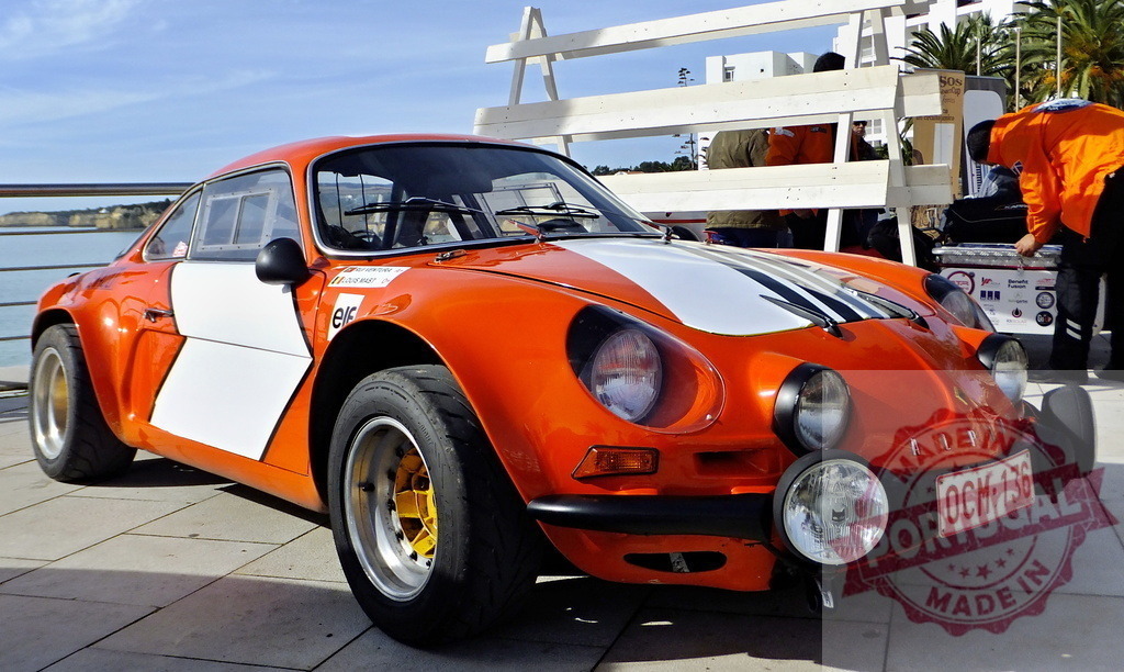 Alpine A110 berlinette 1600s parked near the sea during a rally competition | Orange and white Alpine A110 berlinette 1600s parked near the sea during a rally competition - Realized with Pictrs.com