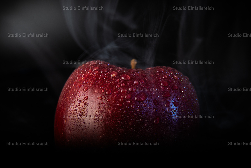 Mystischer roter Apfel mit Wassertropfen und aufsteigendem Nebel | Eine dramatische Nahaufnahme eines tiefroten Apfels auf schwarzem Hintergrund. Die Oberfläche ist mit feinen Wassertropfen bedeckt, während im Hintergrund zarter Nebel oder Dampf aufsteigt. Die dunkle Lichtstimmung verleiht der Frucht eine fast magische, edle Optik. Perfekt für moderne Küchen-Deko, Food-Design oder als Symbol für Gesundheit und Verführung. - Realisiert mit Pictrs.com