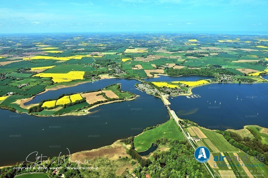 Luftbild Ostseefjord Schlei, Gunnebyer Noor, Badestrand Gunneby, Landschaftsschutzgebiet Schwansener Schleilandschaft, Schneiderhaken, Lindaunisbrücke | Schneiderhaken, Lindaunisbrücke: Direkt am Strand befindet sich ein kostenfreier PKW-Parkplatz, wobei Fahrzeuge über 1,60 Meter Höhe aufgrund einer tief montierten Schranke nicht zufahren können. Von hier aus kann man die Segelboote beobachten, die stündlich um "Viertel vor" durch die Öffnung der Klappbrücke fahren.