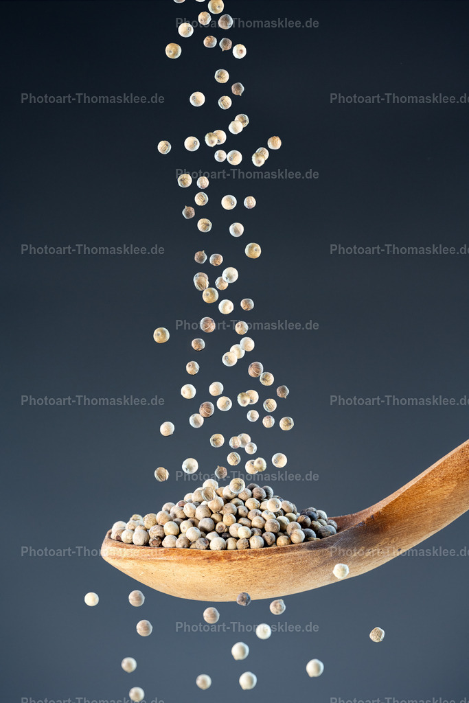 Weißer Pfeffer – mild und aromatisch | Weißer Pfeffer – mild und aromatisch. Kollektion: A spoon of tastefully seasonings.In dieser hochwertigen Studioaufnahme fallen zahlreiche ganze, milde und aromatische weiße Pfefferkörner auf einen rustikalen Holzlöffel herab. Dank der Highspeed-Fotografie ist die Bewegung der Körner perfekt eingefroren, sodass jedes einzelne Detail scharf und klar erkennbar ist. Der dunkle blaugraue Hintergrund mit sanftem Verlauf setzt die hellen Pfefferkörner kontrastreich in Szene und sorgt für eine elegante, zeitlose Stimmung. Die natürliche Maserung des Holzlöffels unterstreicht die Authentizität und Rustikalität der Szene. Dieses Bild verbindet kulinarische Ästhetik mit hochwertiger Fotokunst und eignet sich ideal für Küchen, Feinkostgeschäfte oder moderne Gastronomiebereiche.Wo könnte man dieses Bild am besten aufhängen?In einer modernen Küche oder im Esszimmer als stilvolles Gewürzthemen-Bild für ein harmonisches Ambiente.In Feinkostläden oder Bio-Geschäften, um die natürliche Vielfalt von Gewürzen authentisch zu präsentieren.In Restaurants mit gehobener Küche, speziell in Bereichen, wo kulinarische Handwerkskunst hervorgehoben werden soll.Alu-Dibond: Die matte, elegante Oberfläche von Alu-Dibond verstärkt die Klarheit und Schärfe der eingefrorenen Pfefferkörner und lässt die rustikale Struktur des Löffels modern wirken.Acrylglas: Unter Acrylglas gewinnen die hellen Farbtöne der Pfefferkörner an Leuchtkraft und Tiefe, die Details erscheinen besonders brillant und hochwertig.Poster: Als Poster ist das Motiv leicht integrierbar, bietet große Flexibilität für moderne Küchen oder Feinkostshops und bringt Dynamik in den Raum.Leinwand: Auf Leinwand wirken die natürlichen Materialien wie Holz und Pfeffer besonders harmonisch, was eine warme, gemütliche Stimmung erzeugt. - Realisiert mit Pictrs.com