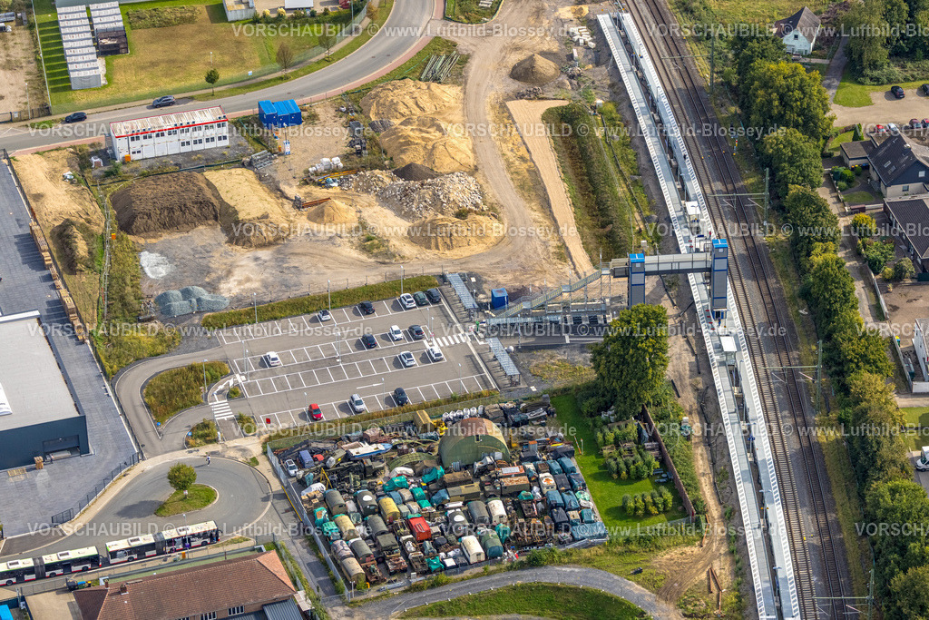 Voerde250904407 | Luftbild, Friedrichsfeld (Niederrhein) Bahnhof, Baustelle mit Neubau und Treppenaufgang zum Bahnsteig mit Fußgängerbrücke, Parkplatz und Fahrradständer, Schrottplatz mit alten Militär-LKWs am Friedrichsfeld Bahnhof, Friedrichsfeld, Voerde, Ruhrgebiet, Nordrhein-Westfalen, Deutschland