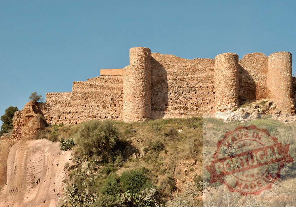 Historic stone fortress walls standing on a hill | Ancient stone fortress walls and towers standing on a hill under a clear blue sky - Realisiert mit Pictrs.com