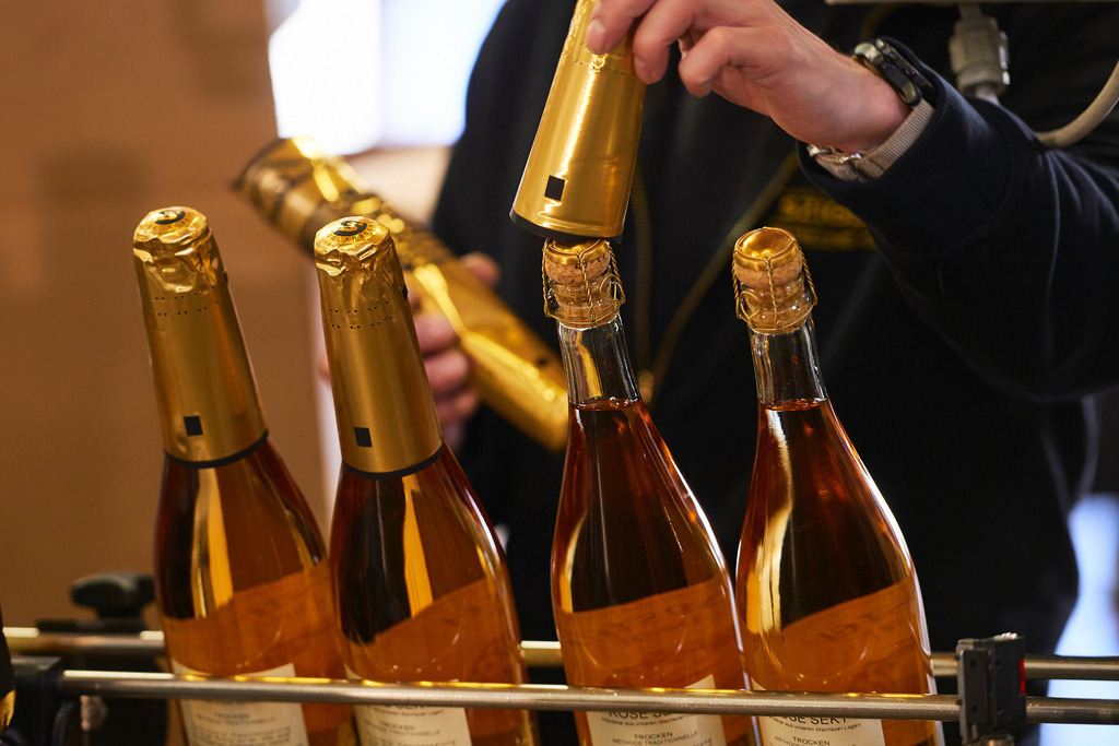 Sektkellerei Szigeti | Gols, Austria - February 19, 2018: Sektkellerei Szigeti; Sektflaschen werden von einem Mitarbeiter mit Sekt-Kappen bestückt. - Realisiert mit Pictrs.com