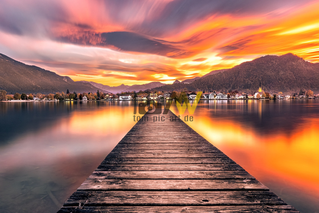 Grandioser Sonnenuntergang---Tegernsee | Die tief stehende Sonne tauchte die komplette Szene dazu, in eine tolle Orange und Rot getönte Atmosphäre ein.Das Bild zeigt den Tegernsee, einen beliebten Ausflugs- und Urlaubsort in Bayern, Deutschland. Der See liegt etwa 50 Kilometer südlich von München in den bayerischen Alpen. Er gehört zu den saubersten Seen Bayerns, was auf eine bereits in den 1960er Jahren geschaffene durchgängige Ringkanalisation zurückzuführen ist. Ansehnliche Berge, wie der 1722 Meter hohe Wallberg, umrahmen den See. Das Ufer ist fast vollständig öffentlich zugänglich, was ihn zu einem beliebten Ziel für Spaziergänge und Radtouren macht.  - Realisiert mit Pictrs.com