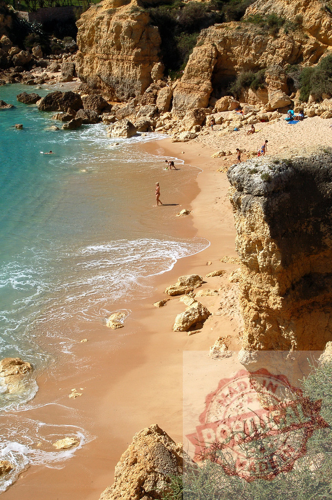 Algarve beach with cliffs, turquoise water, and summer vacationers | People enjoying a sandy beach with eroded cliffs and clear turquoise ocean water on a sunny day - Realized with Pictrs.com