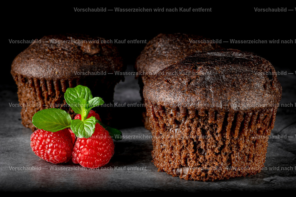 Schokomuffins, dekoriert mit Himbeeren und Minzblatt. | Schokomuffins, dekoriert mit Himbeeren und Minzblatt. Low Key Aufnahme - Realisiert mit Pictrs.com