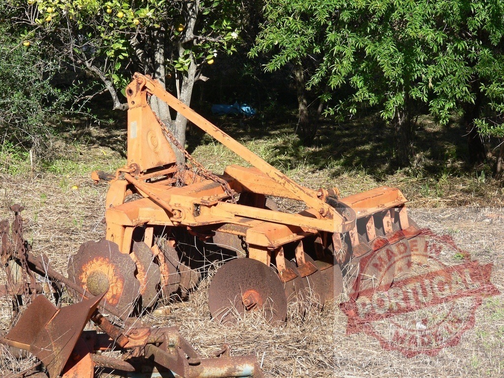 Old rusty agricultural plow disc machine sitting in farm | Old rusty agricultural plow disc machine sitting in a farm field under the shade of trees - Realisiert mit Pictrs.com