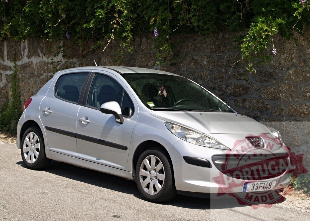 Peugeot 207 hatchback car parked near stone wall | Silver Peugeot 207 hatchback parked on a quiet street near an old stone wall and green foliage - Realisiert mit Pictrs.com