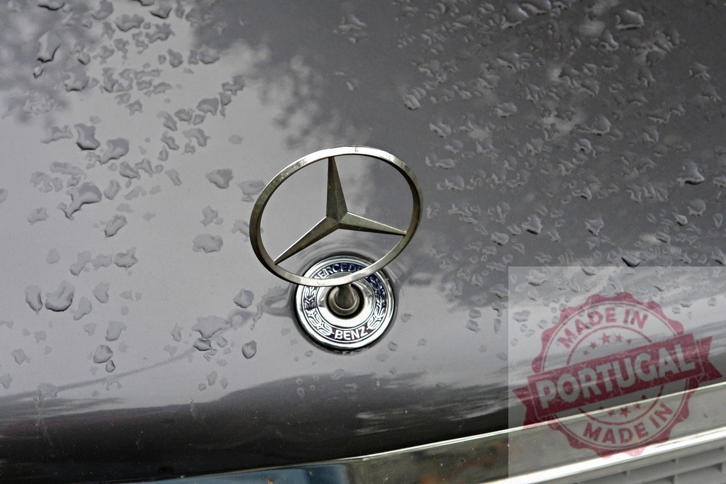 Mercedes-Benz emblem with raindrops on a car hood | Mercedes-Benz hood ornament showing rain droplets on a wet luxury car surface - Realisiert mit Pictrs.com
