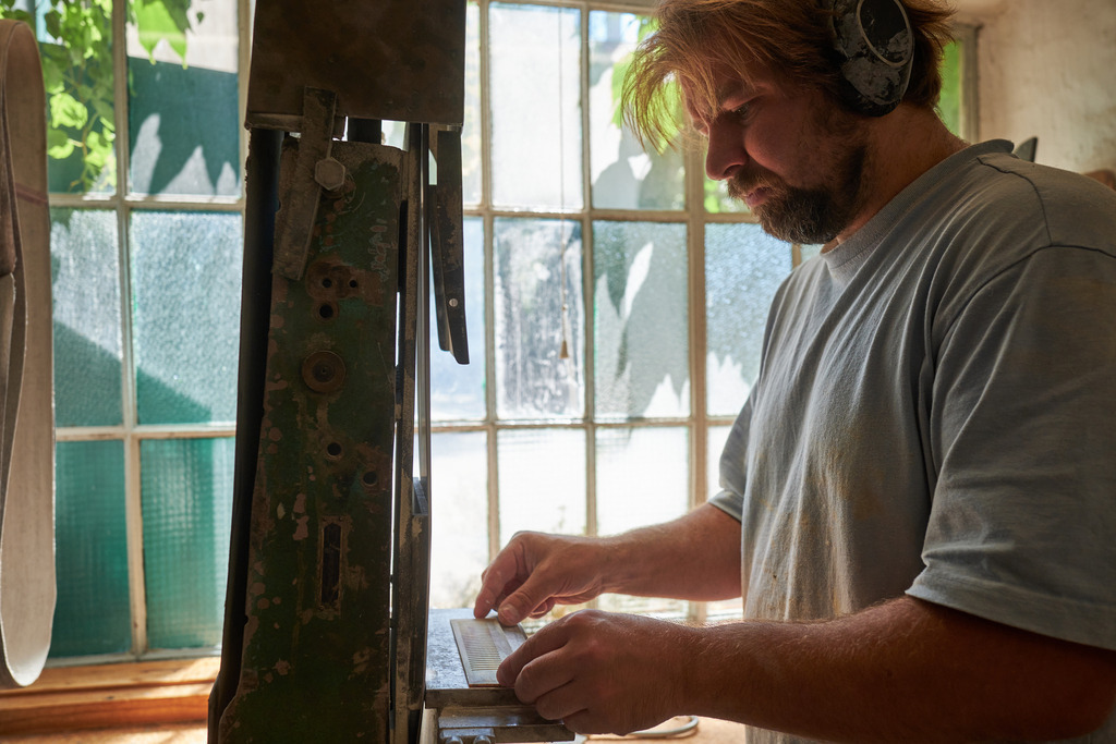 Hornmanufaktur, Herr Petz an der Schleifmaschine | Wien, Austria - August 09, 2022; Hornmanufaktur Thomas Petz; Schleifarbeit in der Werkstatt mit Lärmschutz. - Realisiert mit Pictrs.com