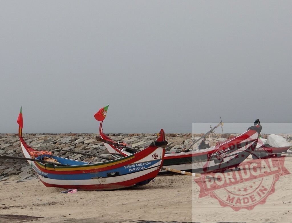 Traditional Portuguese fishing boats with flags on sand | Colorful typical Portuguese fishing boats resting on a sandy beach under a clear sky - Realisiert mit Pictrs.com