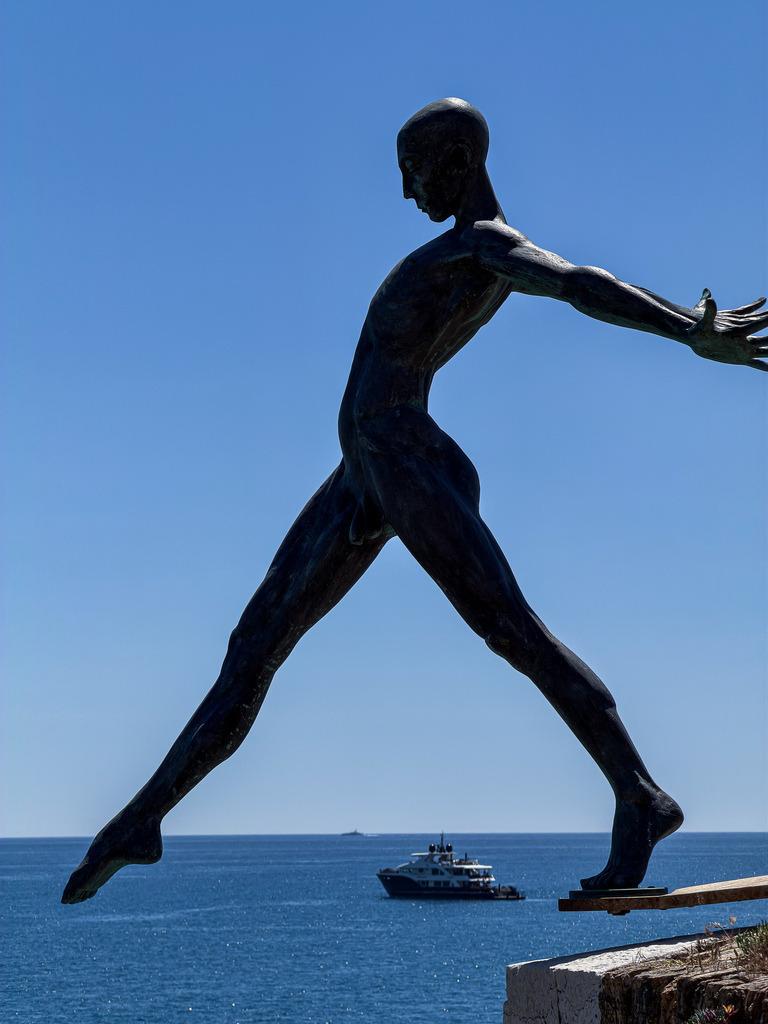 Über dem Meer – Elegante Fotokunst Skulptur Antibes | Eine atemberaubende Symbiose aus Kunst, Architektur und Natur. Diese gestochen scharfe Fine-Art-Fotografie fängt die ikonische Skulptur „Le Nomade“ von Jaume Plensa im französischen Antibes ein. Die filigrane, weiße Silhouette des Wanderers scheint schwerelos über dem tiefblauen Horizont des Mittelmeers zu schweben. Ein hochexklusives Kunstwerk voller Eleganz und Weite, das eine beruhigende, maritime Atmosphäre in moderne Wohnräume, Lofts oder Büros bringt. Optimal als großformatiger Galerie-Druck unter Acrylglas für maximale Farbtiefe. - Realisiert mit Pictrs.com