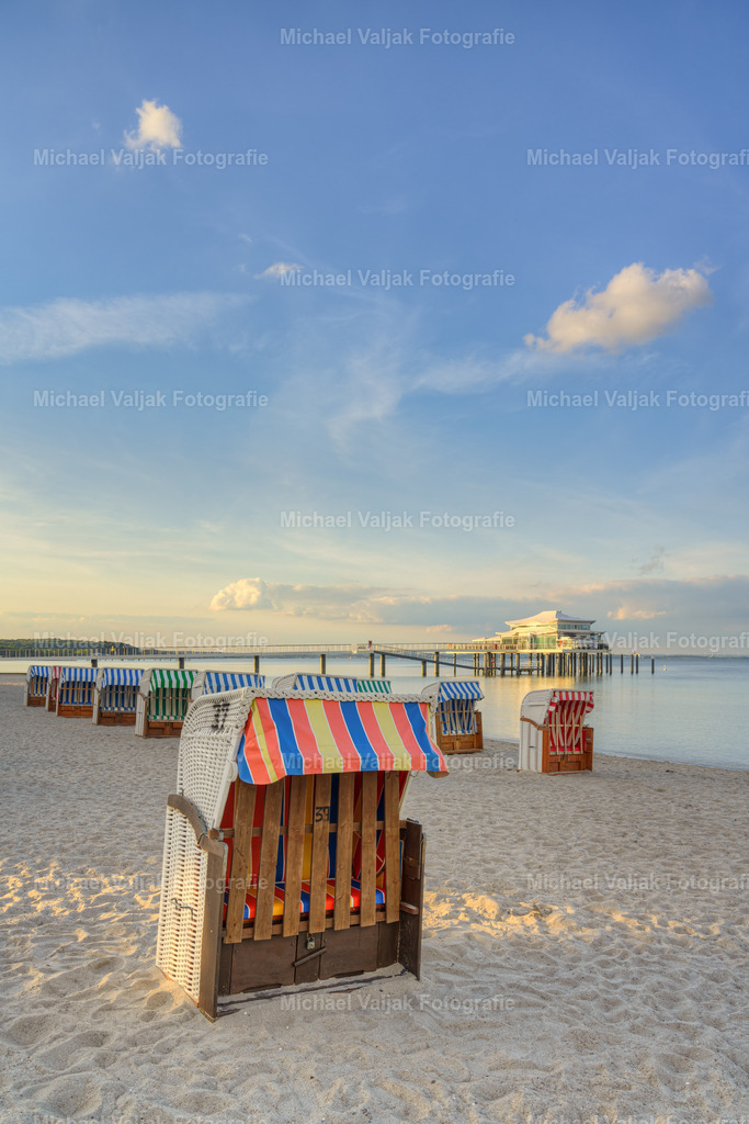 Strandkörbe am Timmendorfer Strand | Abends am Timmendorfer Strand, die letzten Sonnenstrahlen des Tages treffen auf die Seebrücke mit dem Teehaus am Ende und ein kleiner Strahl trifft noch auf den Strandkorb im Vordergrund.  - Realisiert mit Pictrs.com