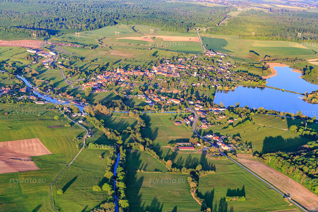 Vue aérienne: Vue de la ville au bord du lac Mittersheim depuis l'ouest à Mittersheim dans le département Moselle, France. Photo: IMG_146192.jpg prise le 01/05/2025 par Werner Riehm/FLY-FOTO.eu – Résolution de l'original: 5472 x 3648 px
