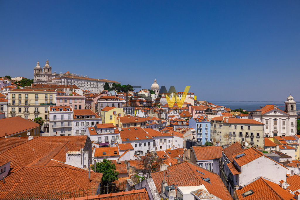 Weiter Blick über die Dächer von Lissabon--Panorama-Horizont | Das Bild zeigt eine Panoramaansicht des historischen Viertels Alfama in Lissabon, Portugal. Alfama ist das älteste und eines der ursprünglichsten Viertel Lissabons. Die Gegend ist bekannt für ihre engen, verwinkelten Gassen und die charakteristischen Häuser mit den roten Ziegeldächern. Zu den markanten Gebäuden im Hintergrund gehören das Kloster São Vicente de Fora (links mit den zwei Türmen) und die Kirche Santa Engrácia (Panteão Nacional, mit der weißen Kuppel in der Mitte). - Realisiert mit Pictrs.com