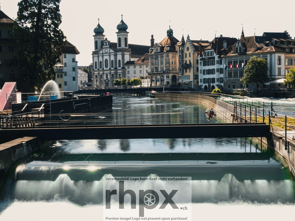 Das Luzerner Nadelwehr | Kraft. Technik. Tradition.Das historische Nadelwehr reguliert seit Generationen den Wasserstand des Vierwaldstättersees und prägt das Stadtbild von Luzern auf einzigartige Weise. Die Kombination aus rauschendem Wasser und der barocken Silhouette der Jesuitenkirche macht diesen Ort zu einem Symbol für die lebendige Geschichte der Stadt.Wähle unter "Produktauswahl" dein Wunschformat: Vom klassischen Wandbild über Puzzle &amp; Tassen bis zum digitalen Download (z.B. als Handy-Hintergrund). - Realisiert mit Pictrs.com