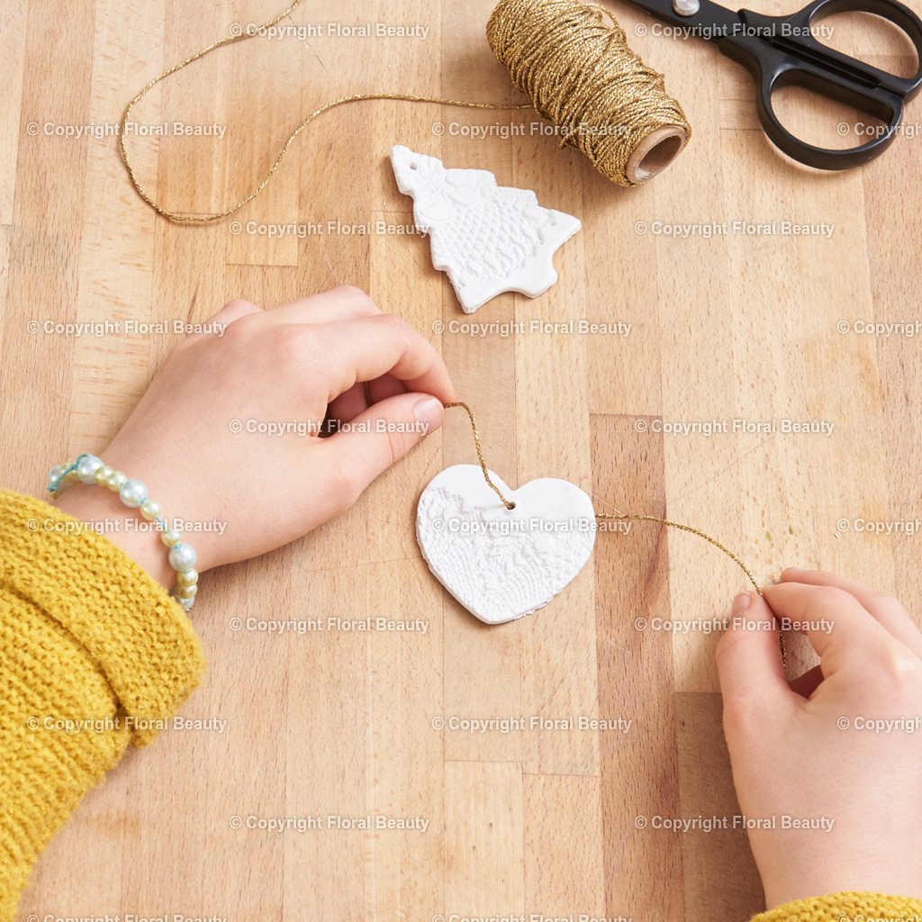 Weihnachtsanhänger aus Fimo | Fimo ausrollen. Spitze auflegen und gut andrücken. Mit Backförmchen Weihnachtsmotive ausstechen. Loch für Aufhängung machen und Faden durchziehen. Im Ofen nach Anleitung backen. - Realisiert mit Pictrs.com