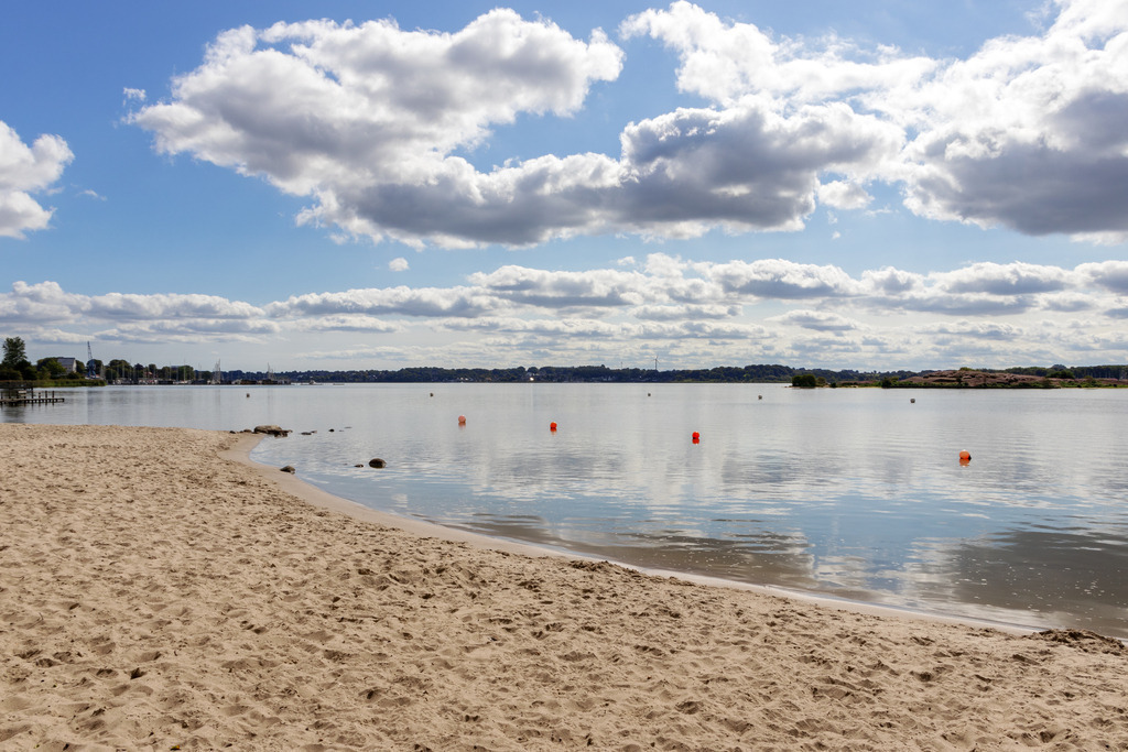 Wandbild: Schleistrand Luisenbad in Schleswig | Dieses Wandbild im Querformat zeigt den Schleistrand am Luisenbad im Sommer. Auf der Schlei ist eine schöne Spiegelung der sommerlichen Wolken zu sehen.  - Realisiert mit Pictrs.com
