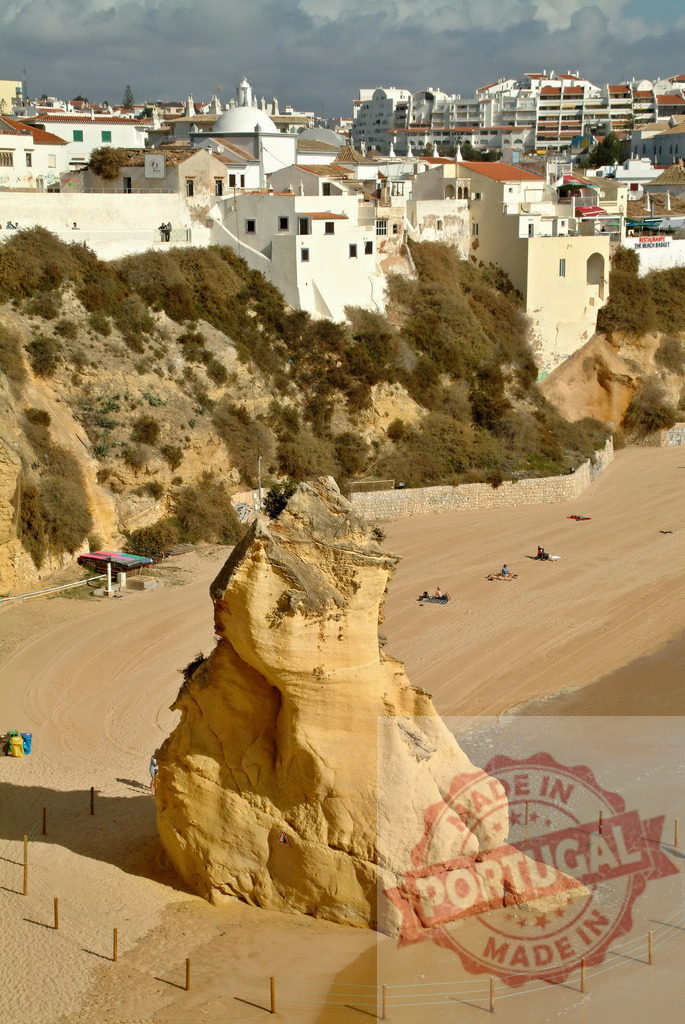 Albufeira beach rock formation with town overview | Limestone rock formation standing on a sandy beach below the town of Albufeira, Algarve - Realized with Pictrs.com