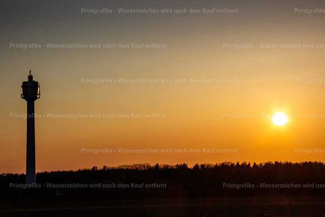 Wachturm im Sonnenuntergang | Minimalistische Landschaftsaufnahme mit einem einzelnen Turm als Silhouette vor warmem Abendhimmel. Die tief stehende Sonne, die klare Horizontlinie und die reduzierte Bildgestaltung erzeugen eine ruhige, grafische Stimmung. - Realisiert mit Pictrs.com