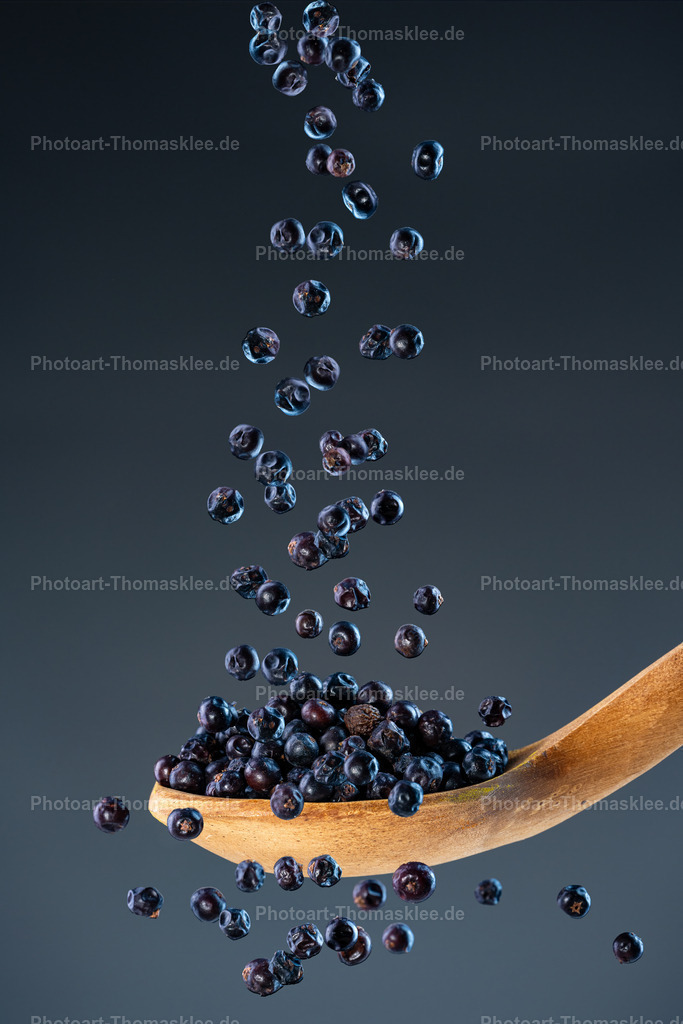Wacholderbeeren – wilde Würze in perfekter Balance | Wacholderbeeren – wilde Würze in perfekter Balance. Kollektion: A spoon of tastefully seasonings.In dieser kunstvollen Foodfotografie stürzen zahlreiche aromatische, tiefblaue Wacholderbeeren auf einen rustikalen, gealterten Holzlöffel und werden in perfektem Moment mit eingefrorener Bewegung festgehalten. Der dunkle blaugraue Hintergrund mit sanftem Farbverlauf setzt die intensiven Farbtöne der Beeren und die raue Struktur des Löffels beeindruckend in Szene. Die Aufnahme besticht durch hohe Detailtreue, brilliante Farben und die Kombination von rustikaler Natürlichkeit mit moderner Bildgestaltung. Ideal für Themen rund um Kulinarik, Naturprodukte, Gewürze und Feinkost.Vorschläge, wo man dieses Bild aufhängen könnteWeinbar oder Feinkostgeschäft – als edler Hingucker für eine hochwertige Atmosphäre.Privates Esszimmer oder Küche – als stilvolle Ergänzung für Liebhaber feiner Gewürze.Boutique-Hotel oder B&amp;B – im Frühstücksraum oder Restaurantbereich für ein einladendes, hochwertiges Ambiente.Alu-Dibond: Die matte, reflexionsarme Oberfläche unterstreicht die Tiefe des dunklen Hintergrunds und verleiht den satten Farben der Wacholderbeeren ein elegantes, professionelles Finish – perfekt für moderne und minimalistische Einrichtungen.Acrylglas: Durch die glasklare Oberfläche erscheinen die Beeren besonders lebendig und plastisch, die Bewegung wird betont, die Farben strahlen brillant – ideal für stylische Küchen, Restaurants oder offene Wohnbereiche.Poster: Als hochwertiges Poster wirkt das Motiv frisch und lebendig, ideal für flexible Dekorationen, insbesondere in gastronomischen Einrichtungen oder Foodtrucks mit wechselnden Themen.Leinwand: Die natürliche Struktur der Leinwand ergänzt die rustikale Anmutung des Holzlöffels perfekt und schafft eine warme, gemütliche Stimmung – besonders schön in ländlichen Küchen oder urigen Cafés. - Realisiert mit Pictrs.com