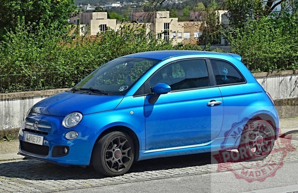 Blue Fiat 500 car parked on cobblestone street | Blue Fiat 500 subcompact car parked on a urban cobblestone street with buildings in background - Realisiert mit Pictrs.com