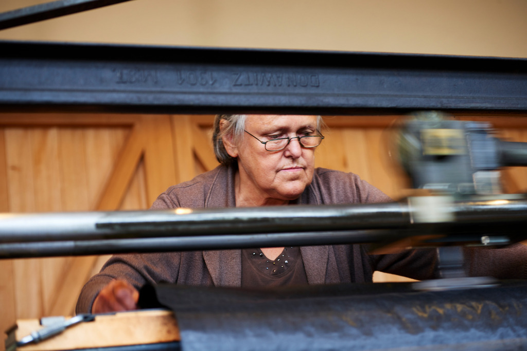 Frau Simma an der Glästmaschine | Riefensberg, Austria - September 12, 2017: Juppenwerkstatt Riefensberg; Frau Simma an der historischen Glästmaschine. - Realisiert mit Pictrs.com