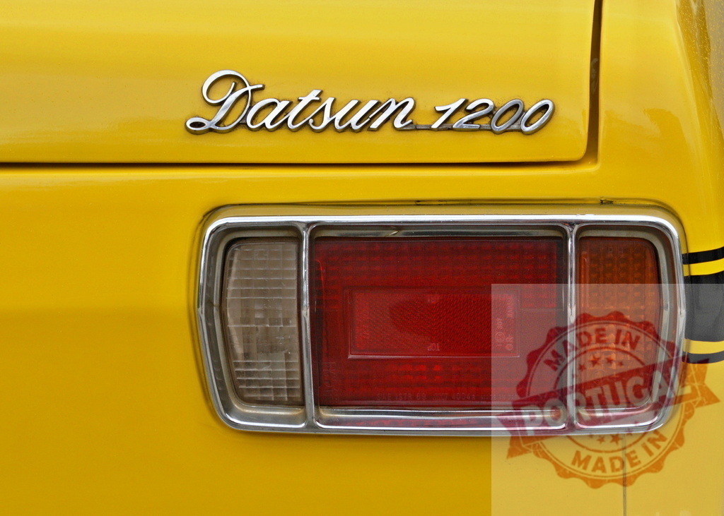 Datsun 1200 yellow vintage car showing back lights and logo | Close-up of the back lights of a yellow vintage Datsun 1200 car, highlighting the brand logo - Realized with Pictrs.com