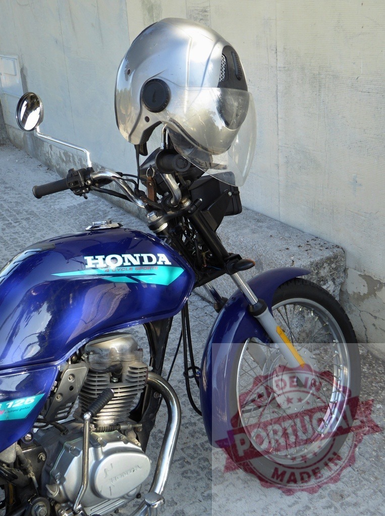 Silver helmet resting on a blue Honda motorcycle handlebar | Modern silver helmet placed on the handlebar of a parked blue Honda motorcycle, offering safety and style for riders - Realisiert mit Pictrs.com