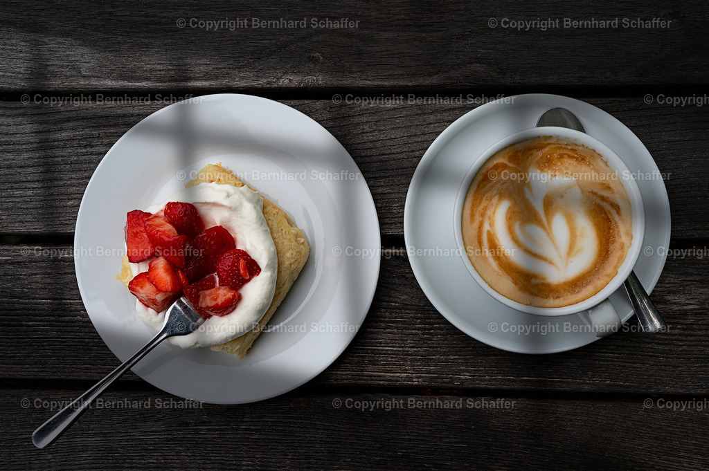 Erdbeerbisquite und Cappuccino | Ein Erdbeerbisquite und eine Tasse Cappuccino stehen auf einem Holztisch. - Realisiert mit Pictrs.com